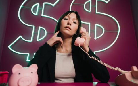 Confident woman on a pink phone with neon dollar signs. Finance theme.