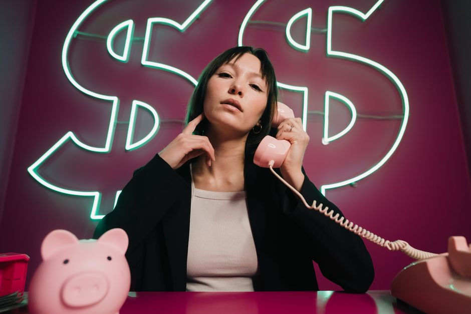 Confident woman on a pink phone with neon dollar signs. Finance theme.