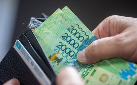 Close-up of hand holding 2000 Kazakhstan Tenge banknotes in a wallet.