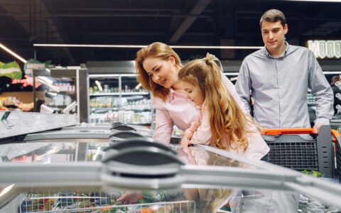 A happy family shopping in the supermarket's freezer section, emphasizing togetherness and love.